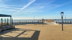 Een verharde promenade met banken en een uitkijkpunt over de zee.