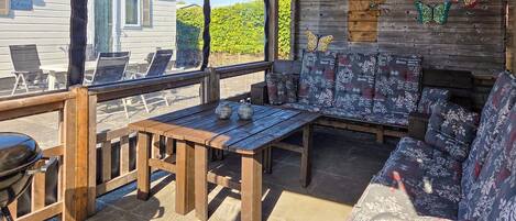 A covered outdoor seating area with wooden furniture, a grill, and a view of a house labeled 'Azure.'