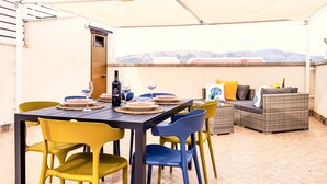 Eine Terrassengruppe im Freien mit Esstisch, Stühlen und einer Couch.