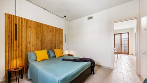Ein Schlafzimmer mit einem Bett, einer Holzwand, einem Nachttisch und einer Tür, die auf einen Balkon führt.
