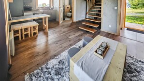 Een moderne, open leefruimte met keuken, eethoek en trap naar een slaapkamer op een entresol.