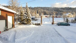 Ein verschneiter Wohnbereich mit einem Haus, einem grünen Auto und einer schneebedeckten Landschaft.