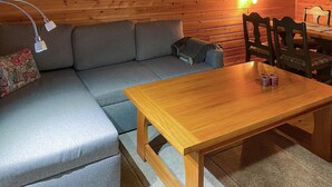 Ein Holzesstisch mit Stühlen, ein graues Sofa und eine Lampe.