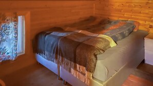 Ein gemütliches Zimmer mit einem Bett, einer Holzwand und floralem Kunstwerk an der Wand.
