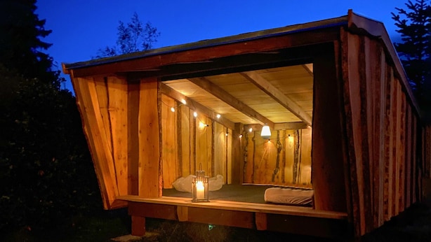 Une cabane en bois avec un lit, une table et un luminaire suspendu.