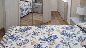 Une chambre à coucher comprenant un lit, une table de chevet, une commode, une fenêtre et une armoire.