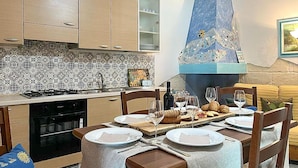 A modern kitchen with a gas stove, sink, and patterned backsplash. There is a dining table set with plates, glasses, and a bottle of wine. - Beautiful home in Torre Colimena with WiFi (Torre Colimena)