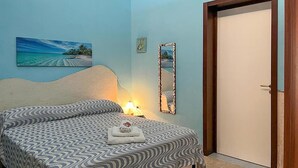 A bedroom with a bed, a nightstand, a wall-mounted mirror, and a door. - Beautiful home in Torre Colimena with WiFi (Torre Colimena)