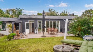A modern house with a patio, a dining area, and a green couch. - Nice home in Anholt with WiFi (Anholt)