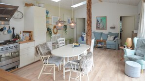 A modern kitchen with a stove, dining table, and chairs. There is a living area with a sofa and a coffee table. - Nice home in Anholt with WiFi (Anholt)