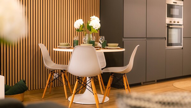 A modern kitchen with a dining table set for four, surrounded by white chairs with wooden legs. - Carmo House - One-bed room Apartment (Faro)