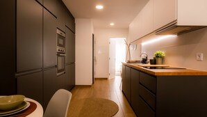 A modern kitchen with dark cabinetry, a wooden countertop, and a round rug. - Carmo House - One-bed room Apartment (Faro)