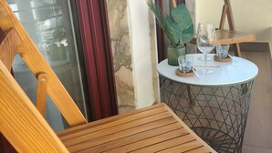 A wooden chair and table on a balcony with a view of buildings and a tower. - Carmo House - One-bed room Apartment (Faro)