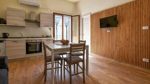 A modern kitchen with a dining area, wooden panel wall, and a flat-screen TV. - 1 bedroom pet friendly apartment in Trappeto (Trappeto)