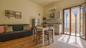 A compact living space with a sofa, dining table, and chairs, a kitchenette, and a sliding glass door to a balcony. - 1 bedroom pet friendly apartment in Trappeto (Trappeto)