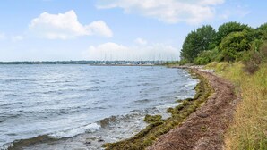 A coastal view with a rocky shoreline, a grassy path, and sailboats in the distance. - Nice apartment in Egernsund with WiFi (Egernsund)