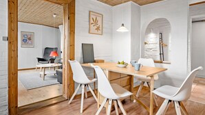 A modern dining area with a wooden table, white chairs, and a large window with a view of the city. - Nice apartment in Egernsund with WiFi (Egernsund)