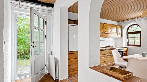 A modern kitchen with white cabinets, wooden accents, and a view of greenery outside. - Nice apartment in Egernsund with WiFi (Egernsund)