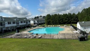 A swimming pool surrounded by lounge chairs and a fenced area, with a building in the background. - Golf Getaway, 5 miles to Pinehurst (Carthage)