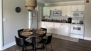 A modern kitchen with white cabinets, a microwave, a stove, and a coffee sign on the wall. - Golf Getaway, 5 miles to Pinehurst (Carthage)