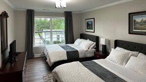 A hotel room with two beds, a large window with curtains, a flat-screen TV, and framed pictures on the walls. - Golf Getaway, 5 miles to Pinehurst (Carthage)