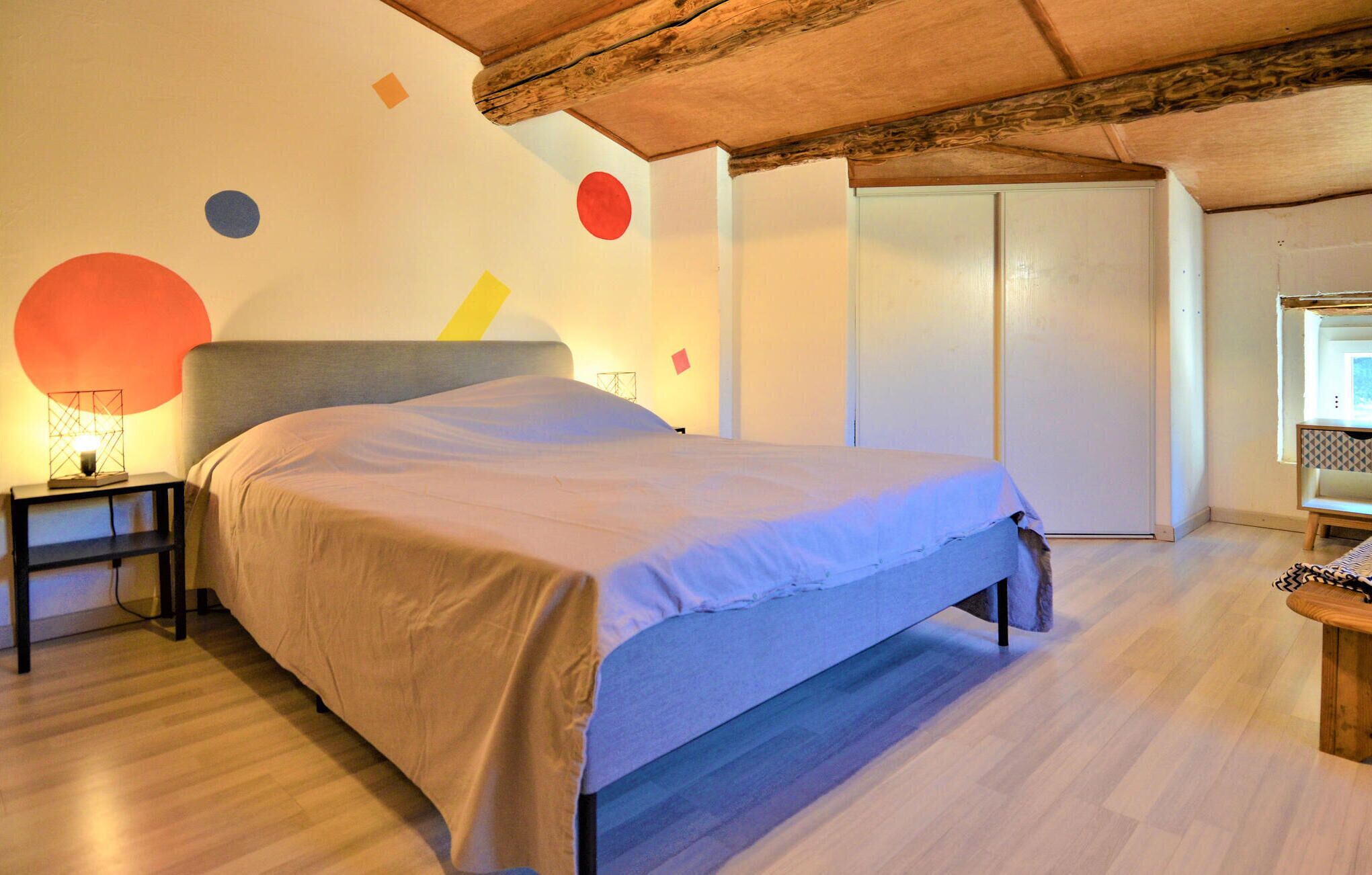 Une chambre à coucher avec un lit, une table de chevet, une lampe et un plafond en bois.