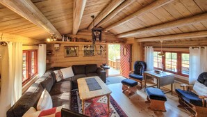 L’intérieur chaleureux d’un chalet avec un plafond en bois, un canapé, une table à manger et une chaise.