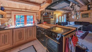 Une cuisine chaleureuse avec des meubles en bois, un poêle et une grande fenêtre.