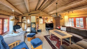 L’intérieur d’un chalet confortable, avec un coin repas, un canapé et une cuisine.