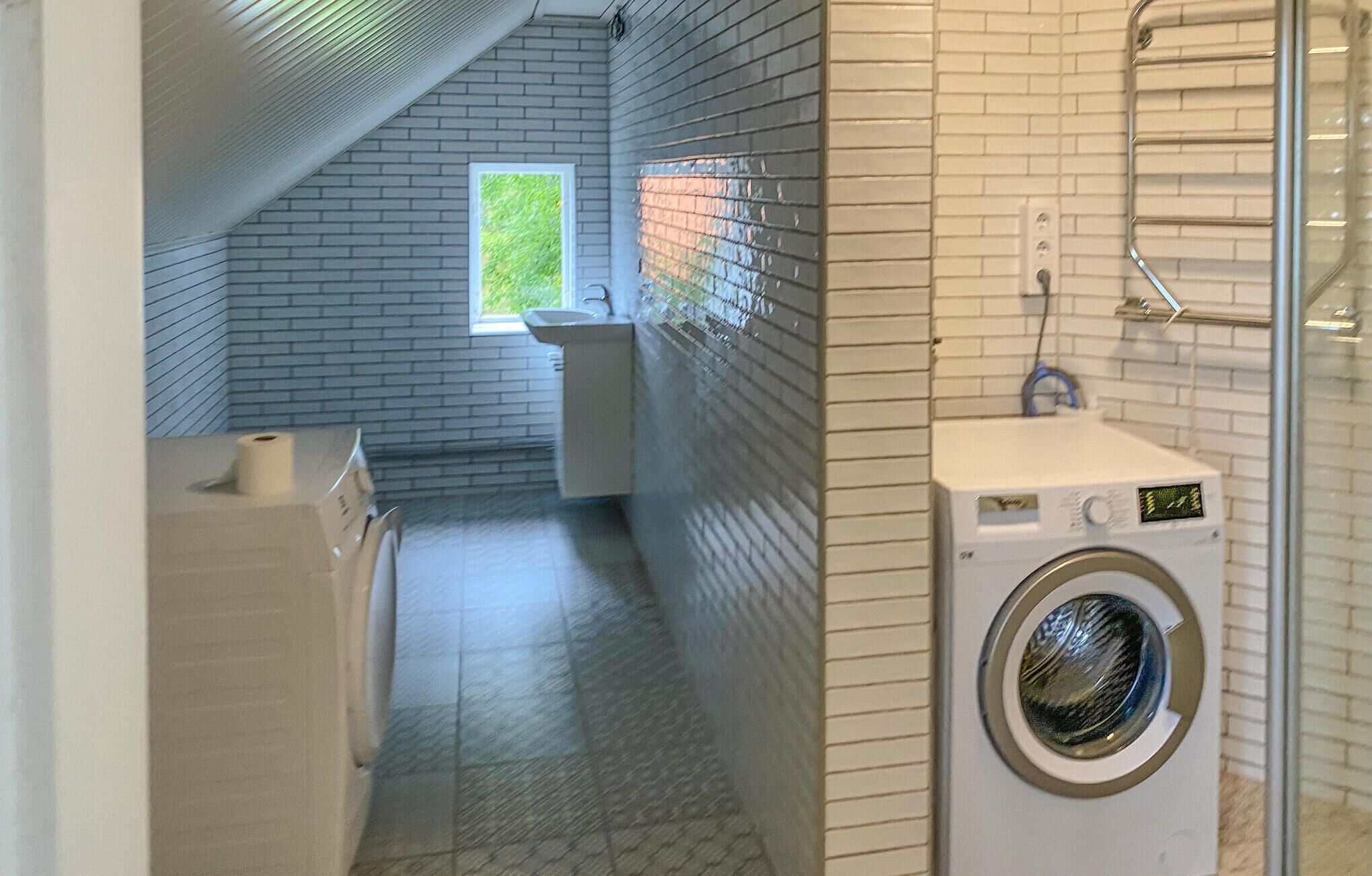 Een wasruimte met een wasmachine, een wasbak en een raam.
