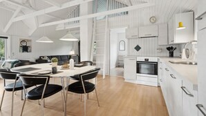 A spacious kitchen with white cabinetry, a built-in oven, and a dining area with a round table and black chairs.