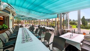 A covered outdoor dining area with tables and chairs, large windows, and a view of the garden. - Cozy home in Oberharz with WiFi (Oberharz)