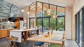 A modern kitchen with a large island, wooden cabinets, and a dining area with a table and chairs. - Gorgeous home in Højby with sauna (Højby)