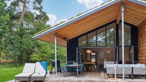 A modern house with a wooden deck, outdoor seating, and a large glass door leading to an interior space. - Gorgeous home in Højby with sauna (Højby)