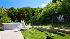 A backyard with a swimming pool, a decorative flamingo statue, a dartboard, and a small garden area.