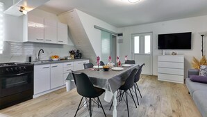 A modern kitchen with white cabinets, a black stove, and a dining area with a table set for four.
