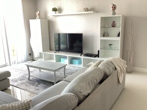 Relax in this stylish living room with a large flat-screen TV, comfortable sofa, and a small coffee table.