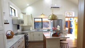Une cuisine moderne avec des meubles blancs, un grand îlot central et un luminaire suspendu.