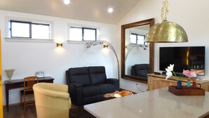 Un salon moderne comprenant un canapé, un fauteuil, une table basse, un téléviseur et un grand miroir.