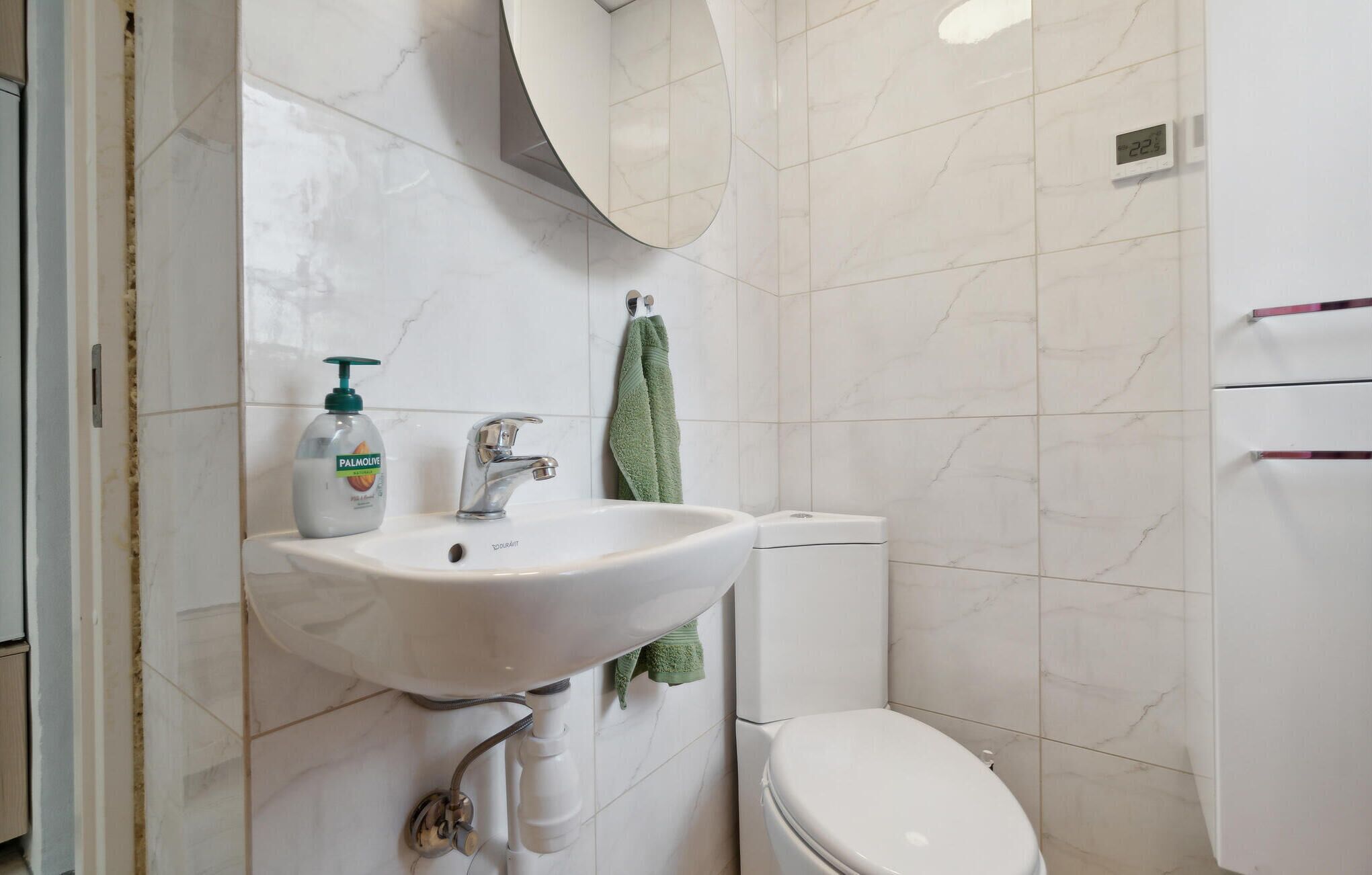 Ein Badezimmer mit Waschbecken, Handtuch, Toilette und Spiegel.
