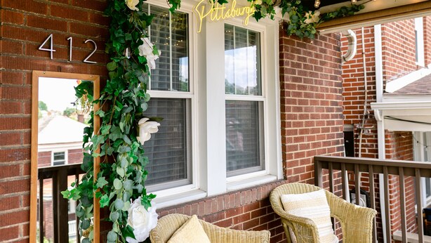 A brick exterior with a number '412' sign, a mirror, and two wicker chairs with cushions. - Vintage inspired 2 bdr home in Pittsburgh near city views (Pittsburgh)