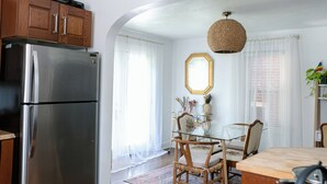 A kitchen with a stainless steel refrigerator, wooden cabinets, a dining table with chairs, and a hanging light fixture. - Vintage inspired 2 bdr home in Pittsburgh near city views (Pittsburgh)