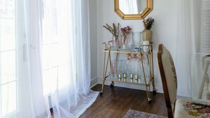 A room with wooden flooring, a patterned rug, a gold-framed mirror, and a glass stand with decorative items. - Vintage inspired 2 bdr home in Pittsburgh near city views (Pittsburgh)