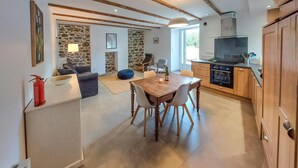 Une cuisine moderne avec des meubles en bois, un four encastré et un coin repas comprenant une table et des chaises en bois.
