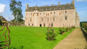 Un grand bâtiment en pierre doté de nombreuses fenêtres et d’une pelouse bien entretenue.