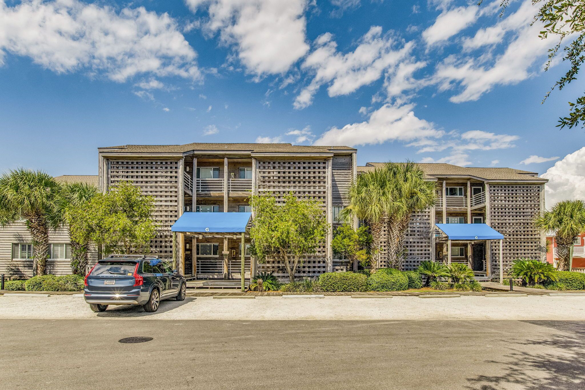 A multi-story hotel with a modern design, featuring balconies and covered outdoor seating areas.