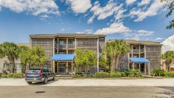 A multi-story hotel with a modern design, featuring balconies and covered outdoor seating areas.