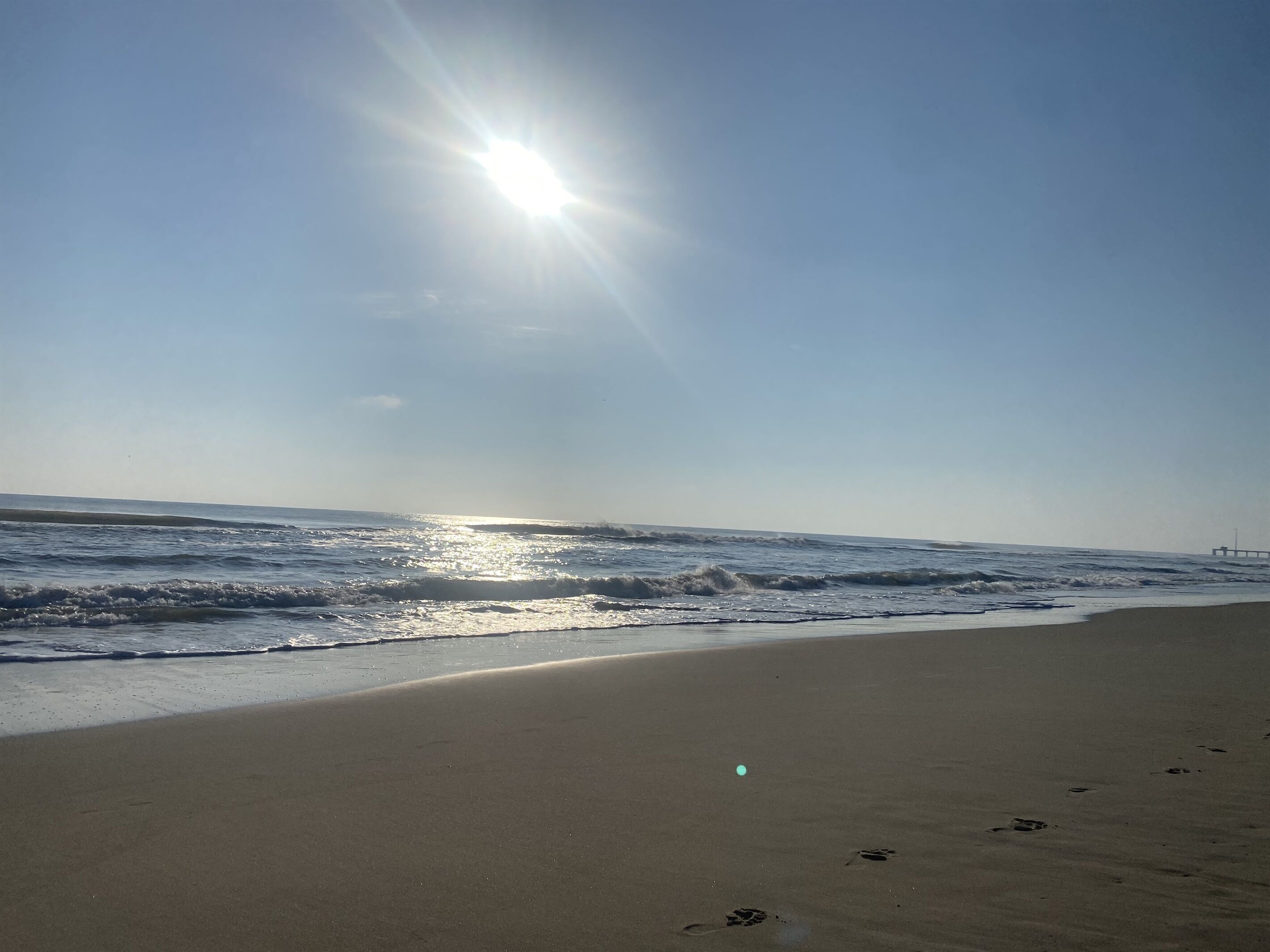 Una spiaggia con cielo sereno e luce solare che si riflette sull'acqua.