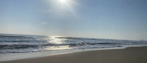 Una spiaggia con cielo sereno e luce solare che si riflette sull'acqua.