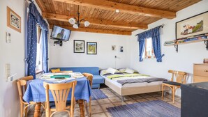 Una habitación acogedora con una cama, una mesa con sillas, un televisor y una estantería.